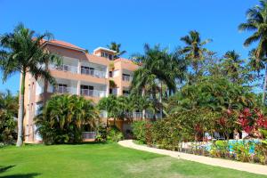 un gran edificio de apartamentos con palmeras y un parque en Caoba en Las Terrenas