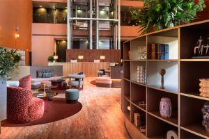 eine Lobby mit einer Bibliothek mit Stühlen und Tischen in der Unterkunft Meliá Bilbao in Bilbao