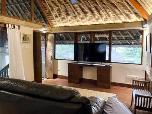 a living room with a couch and a flat screen tv at Villa Layangan - Two Bedrooms with Pool Access in Sanur