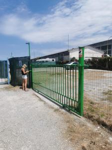 a woman standing next to a green fence at Sonček 2 in Izola