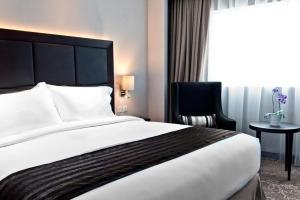 a hotel room with a large bed and a chair at Meliá Makassar in Makassar