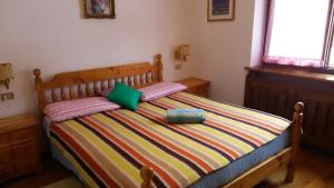 ボルカ・ディ・カドーレにあるTitti house Cortina Dolomitesのベッドルーム1室(カラフルなストライプ毛布付きのベッド1台付)
