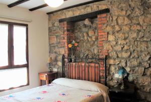 a bedroom with a stone wall with a bed at Apartamentos Maite in Oreña