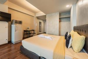 a bedroom with a bed and a kitchen with a refrigerator at BKK39 Airport Hotel in Lat Krabang