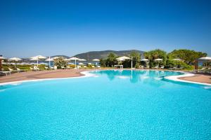 ein großer Swimmingpool mit blauem Wasser und Sonnenschirmen in der Unterkunft Hotel Corte Rosada - Adults Only, Affiliated by Meliá in Porto Conte