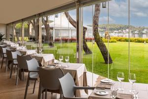 ein Restaurant mit Tischen und Stühlen und einem großen Fenster in der Unterkunft Hotel Corte Rosada - Adults Only, Affiliated by Meliá in Porto Conte