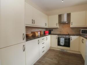 a kitchen with white cabinets and a wooden floor at West End House in Bradford +19 photos