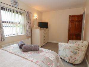 a bedroom with a bed and a chair and a television at West End House in Bradford