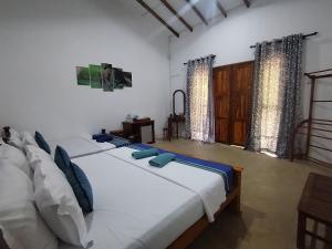 two beds in a room with white walls and blue pillows at Wilpattu Wild Villa in Pahala Maragahawewa +240 photos