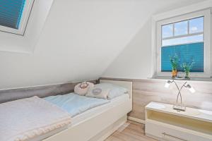 a white bedroom with a bed and a window at Am-Nordmeerstrand in Norddeich