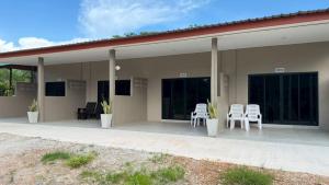 a house with white chairs and windows on a patio at I mee Lanta Home in Phra Ae beach