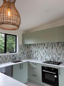 a kitchen with white cabinets and a chandelier at The palms farmhouse in Puketona +15 photos
