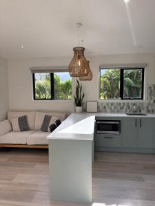a kitchen and living room with a couch and a chandelier at The palms farmhouse in Puketona