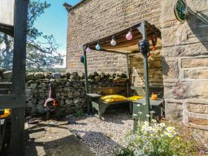 a garden with a stone wall and a wooden structure at Moldy Warp Barn in Keighley