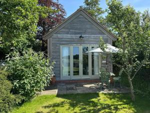 a small house with a patio and an umbrella at The Lodge at Mortons in Malmesbury