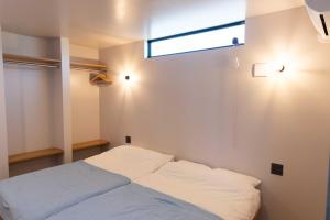 a small bedroom with a bed with a window at ウミチカ in Minamiboso
