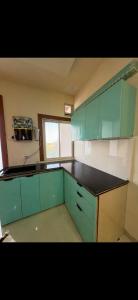 a kitchen with green cabinets and a black counter top at Cube Stay in Bhopal