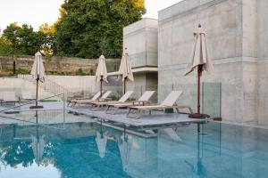 a pool with chairs and umbrellas next to a building at INNSiDE by Meliá Braga Centro in Braga