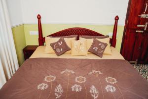 a bed with brown pillows and a brown blanket at Illam By Santhi in Varkala +16 photos