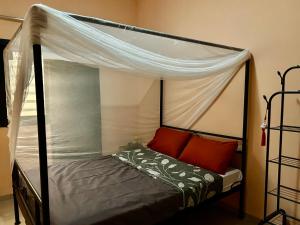 a bedroom with a canopy bed with red pillows at Chambre avec salle d eau privée in Mbour