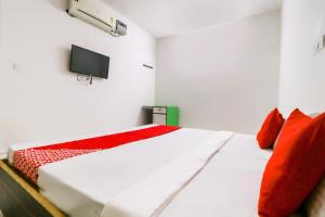 a bedroom with a bed with red pillows and a tv at Hotel O Sky Garden in Ludhiana