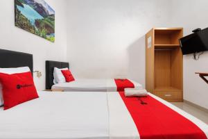 a bedroom with two beds with a red and white blanket at RedDoorz @ Jalan Danau Limboto in Malang