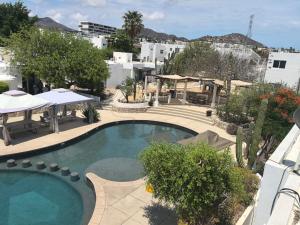 a swimming pool with a table and umbrellas next to a building at Casa Tezal Alberca in Cabo San Lucas