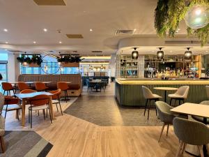 a restaurant with tables and chairs and a bar at Holiday Inn London Luton North in Luton