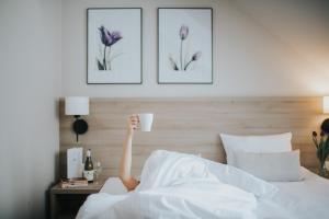 osoba leżąca w łóżku pijąca filiżankę kawy w obiekcie Tulipanowy Gościniec w mieście Jantar