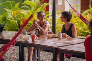 two women sitting at a table with a bottle of beer at Kalunay Hostel - Breakfast included in Puerto Viejo