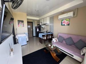a living room with a purple couch and a kitchen at Cozy apartment with a sea view in Ban Bo Sai Klang