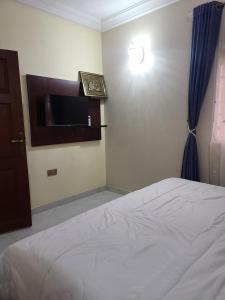 a bedroom with a bed and a clock on the wall at Cogent Apartments and Hotel in Uyo