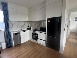 a kitchen with white cabinets and a black refrigerator at 2 Bedroom Granny Flat in Runciman
