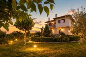 a house with lights in the yard at dusk at Olive View Cottage in Pelion in Platanidia