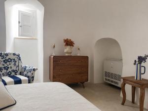 a bedroom with a bed and a dresser and a chair at I Trulli di Federico in Selva di Fasano