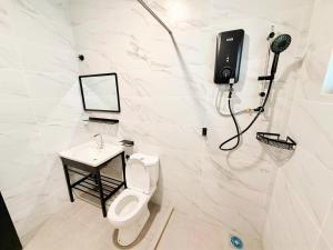 a bathroom with a toilet and a phone on the wall at Pertama Lodge in Tawau