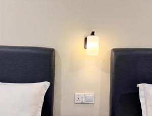 two beds with black headboards and a light on the wall at Pertama Lodge in Tawau