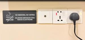 a wall with a plug in a lightswitch and a plug in a socket at Pertama Lodge in Tawau +41 photos