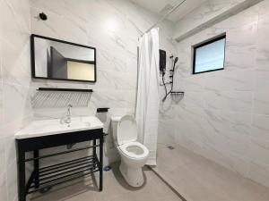 a white bathroom with a toilet and a sink at Pertama Lodge in Tawau