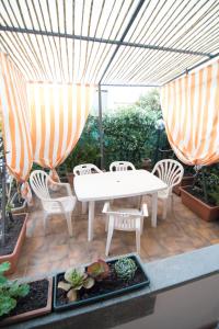 un patio con una mesa blanca, sillas y sombrillas en Holiday House Torre del Lago, en Torre del Lago Puccini