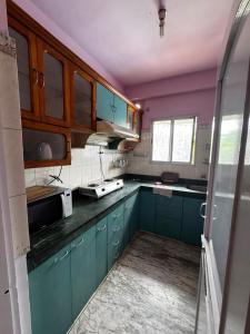 a kitchen with blue cabinets and purple walls at Subba Stays in Siliguri
