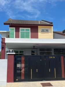 a house with a black gate in front of it at Villa Hayfa in Kuala Kerai