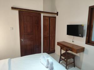 a bedroom with a bed and a desk and a television at Moonrise Rooms in Uluwatu
