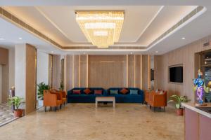 a lobby with a blue couch and orange chairs at Enrise By Sayaji Somnath in Somnath