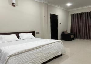 a bedroom with a large white bed and a chair at Palm Breeze Villa in Mannar