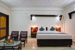 a bedroom with a bed and two chairs and a table at Hotel Prithvi Studio - RDC And Santosh Hospital in Ghaziabad