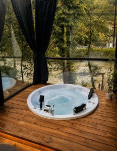 a bath tub on a wooden deck with a large window at MOLVA Bungalows Otel in Çamlıhemşin
