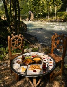 a plate of food on a table next to a river at MOLVA Bungalows Otel in Çamlıhemşin