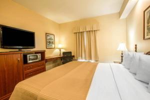 a hotel room with a large bed and a flat screen tv at Quality Inn Greeneville - Tusculum in Greeneville
