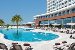 a swimming pool with lounge chairs and a building at Hampton by Hilton Marjan Island in Ras al Khaimah